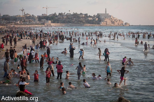 Palestinians from the West Bank enjoy the Mediterranean Sea on the last day of the Eid al-Fitr holiday, Tel Aviv, August 11, 2013. The three-day Eid al-Fitr holiday marks the end of the holy fasting month of Ramadan. The Israeli army generally issues entry permits to Palestinians during Ramadan, allowing many to visit the beach for the first time. (Activestills.org)