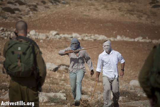 File photo of settlers threatening Israeli activists and Palestinians with sticks in front of the Ma´on settlement, South Hebron hills. (Photo by: Oren Ziv/Activestills.org)