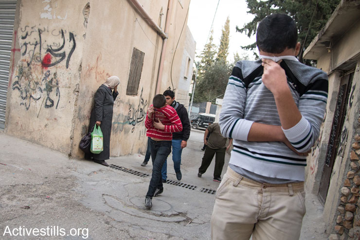Residents of Aida Refugee Camp react to tear gas fired by Israeli forces during clashes in nearby streets, Bethlehem, West Bank, January 21, 2014. (photo: Ryan Rodrick Beiler/Activestills.org)