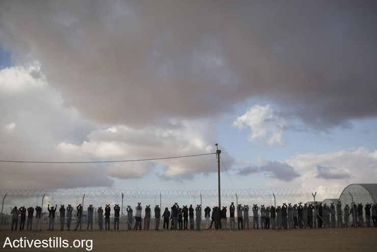 African asylum seekers jailed in Holot detention center protest behind the prison's fence, as other asylum seekers take part in a protest outside the facility, in Israel's southern Negev desert, February 17, 2014. 