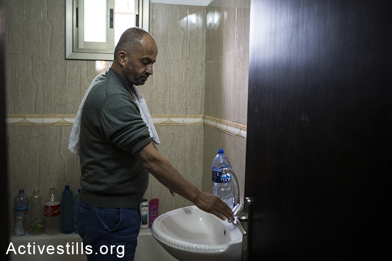 Member of the Swetti family checks the water tap,  East Jerusalem, March 15, 2014. The family of nine, living in the Ras Shehada neighborhood has been going 10 days without running water. (Activestills.org)