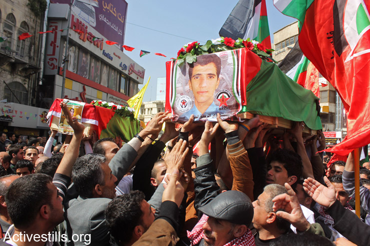 Hundreds of Palestinians participate in a burial ceremony for Palestinian killed between 2001- 2003, Nablus, West Bank, March 19, 2014. On Tuesday, March 18, 2014, Palestinians received the remains of four Palestinian fighters at the Taibeh checkpoint in the West Bank city of Tulkarm. Israel still holds hundreds of Palestinian bodies in an isolated cemetery in Jordan Valley, West Bank. (photo: Activestills.org)