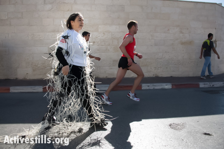 In solidarity with Palestinian prisoners, artist Rana Bishara competes in the second annual Palestine Marathon covered in plastic zip ties like those used by Israeli forces when making arrests, Bethlehem, West Bank, April 11, 2014. (photo: Activestills.org)