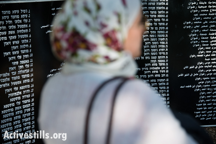 A Palestinian woman stands in front of panels bearing the names of those who died in the Deir Yassin massacre, Givat Shaul, West Jerusalem, April 10, 2014. On April 9, 1948, some 100-200 Palestinians, including women and children, were killed by the extremist Zionist militias the Irgun and Stern Gang (Lehi) in the village of Deir Yassin. The Israeli activist group Zochrot ("remembering") organizes an annual procession to commemorate those killed and to recount the history of the village. (photo: Activestills.org)