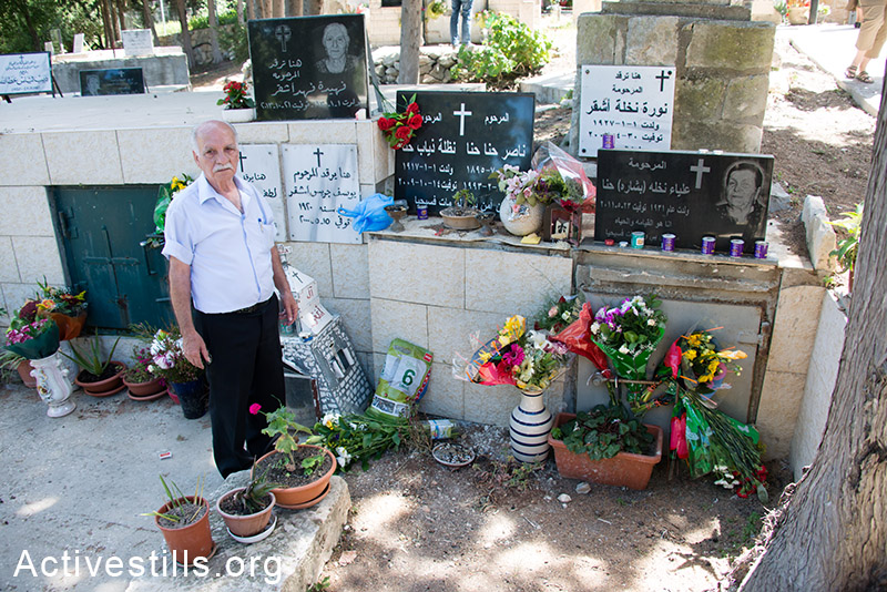Hanna Nasser stands near his family graves in the cemetery of the displaced Palestinian village of Iqrit in northern Israel, April 21, 2014. Iqrit's original inhabitants were forcibly evacuated in the Nakba of 1948. Though the Israeli high court granted the residents, who are Palestinian citizens of Israel, the right to return to their homes in 1951, the military destroyed the village and has since prevented their return. Only the village's church and cemetery remained intact, and are still used by village residents while they campaign for a full return. (Activestills.org)