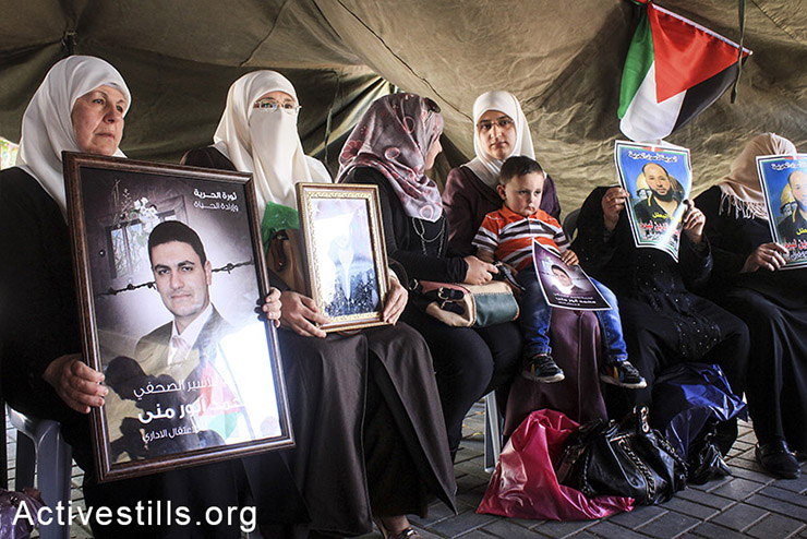 Palestinian women hold pictures of administrative prisoners during the first day of a solidarity protest in the city center of Nablus, West Bank, April 28, 2014. (Ahmad al-Bazz/Activestills.org)