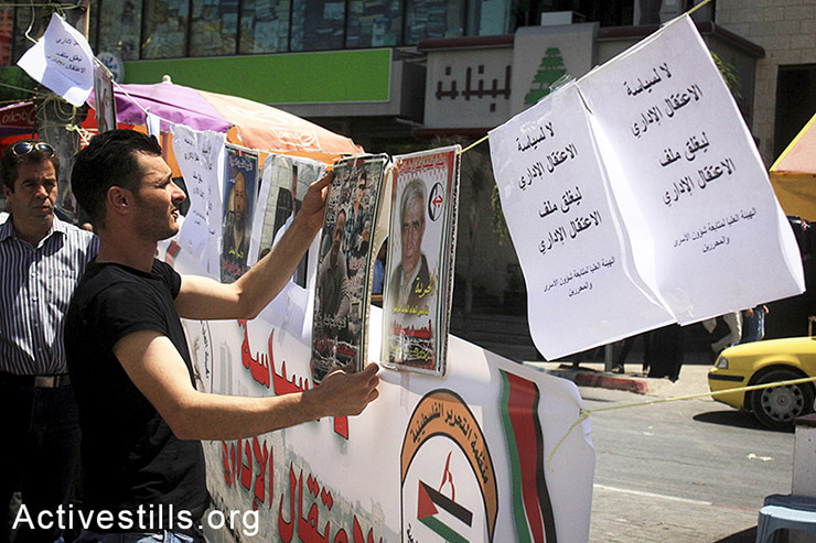A Palestinian hangs pictures of administrative prisoners on the first day of a solidarity protest tent erected in the city center of Nablus, West Bank, April 28, 2014. (Ahmad al-Bazz/Activestills.org)
