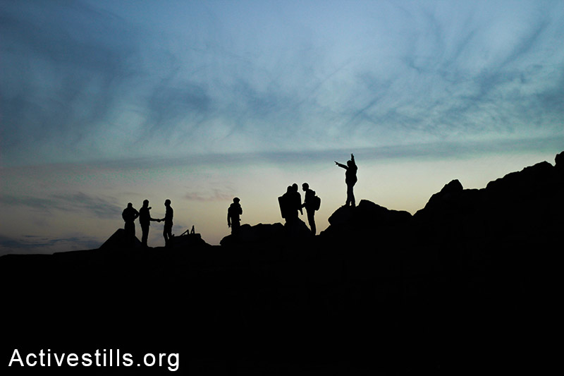 Young men stand on rocks during the sunset at Gaza seaport. (Basel Yazouri/Activestills.org