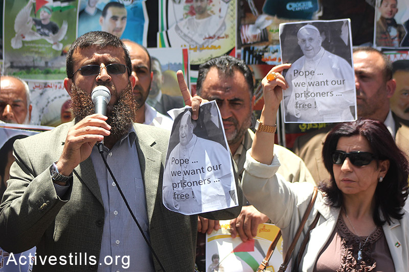 The former Palestinian prisoner Khader Adnan holds a picture of Pope Francis calling him to take action on the Palestinian prisoners' issue, during a  demonstration in solidarity with hunger-striking Palestinian administrative prisoners, Nablus, West Bank, May 25, 2014. More than 100 Palestinian administrative prisoners in Israeli jails launched a mass, open-ended hunger strike on Thursday, April 24, 2014. A few of them are now hospitalized in Israeli medical centres due to the strike. (Ahmad al-Bazz/Activestills.org)