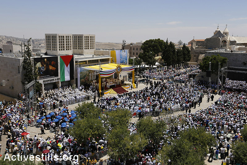 A general view on Manger Square in the West Bank town of Bethlehem where Pope Francis celebrated an open-air mass next to the Church of the Nativity, believed by many to be the birthplace of Jesus Christ, on May 25, 2014, with the colours of the Palestinian flag in the foreground. (Mustafa Bader/Activestills.org)