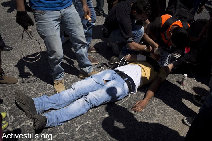 A Palestinian youth lies on the ground after he was shot and injured by the Israeli army during the weekly protest against the occupation in the West Bank village of Nabi Saleh, May 2, 2014.