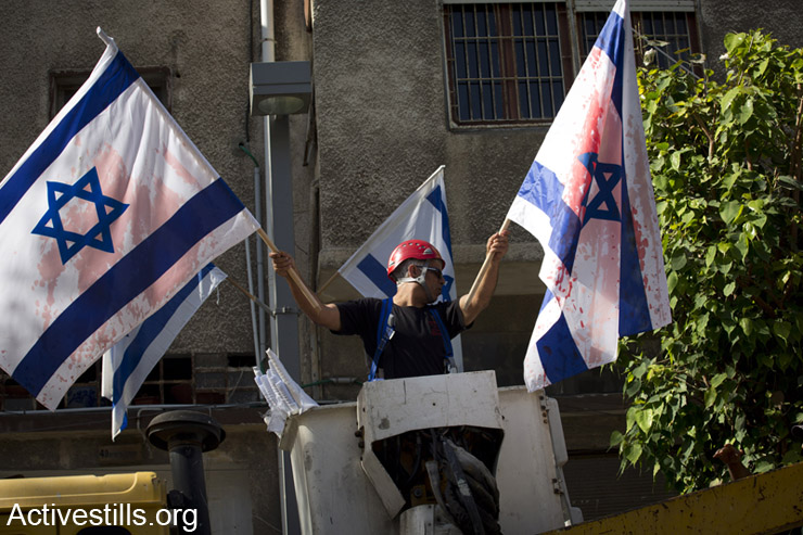 A Tel Aviv municipality worker replaces Israeli flags that were painted during the night with red paint, in the city of Jaffa, May 1, 2014. The Tel Aviv municipality hung the flags a week before the Israeli independence day.