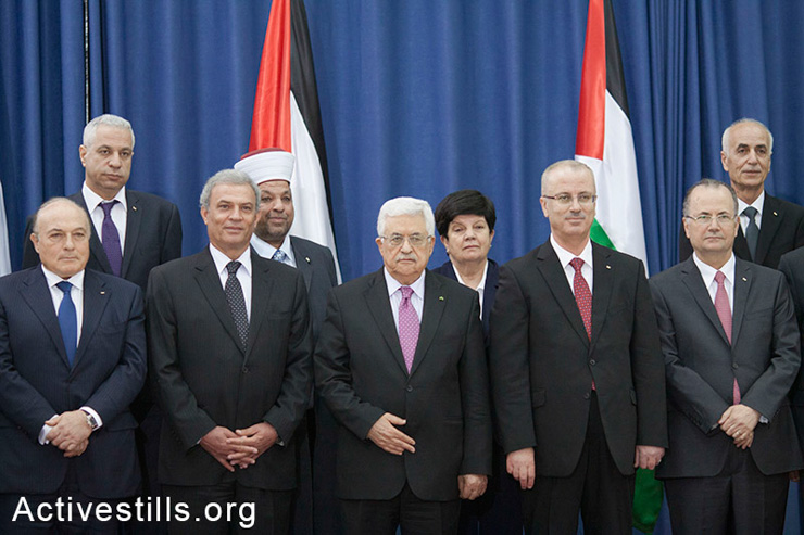 Palestinian president Mahmud Abbas (C) poses for a picture with the members of the new Palestinian unity government in the West Bank city of Ramallah June 2, 2014. Abbas hailed the 'end' of Palestinian division as a new government took its oath under a unity deal between leaders in the West Bank.