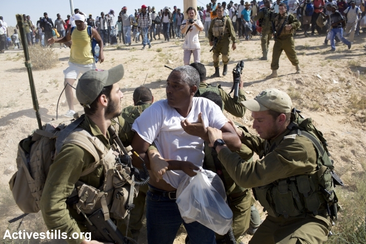 Israeli soldiers try to stop African asylum seekers as they march from the Holot detention center, in which they are jailed, to the Israeli-Egyptian border in protest of Israel's asylum policies, calling on the UN and the Red Cross to intervene, Negev, June 27, 2014. More than 800 Asylum seekers tried to reach to the border fence with Egypt, saying Israeli does not check their asylum requests and therefore they are asking to be resettled in third countries. The group was stopped by the Israeli army and spent the night in a small forest located a few hundred meters from the border. (Photo by Oren Ziv/Activestills.org)