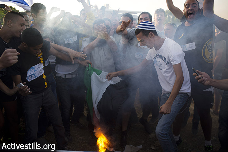 Right wing Israelis burn a Palestinian flag and shout racist slogans during an anti-Palestinian demonstration at the Gush Etzion junction, a settlement next to the Palestinian town of Bethlehem ,on June 16, 2014. (Oren Ziv/Activestills.org)