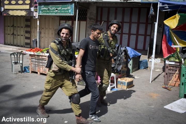 Israeli soldiers smile as they arrest a Palestinian man in Hebron. The army has put the city under closure while it searches for three kidnapped teenagers. (photo: Activestills.org)