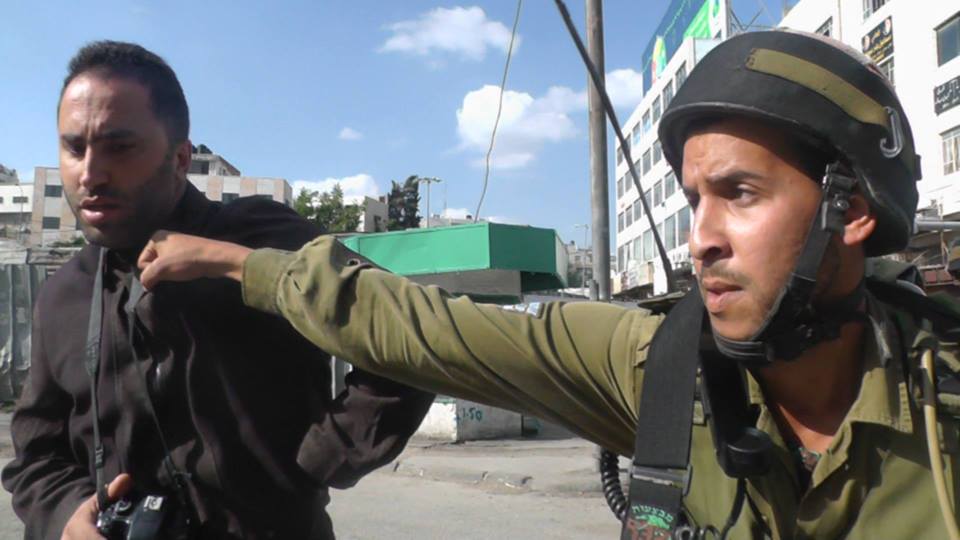 IDF soldier punching Issa Amro in Hebron (photo: Awni Abu Shamsieh) 