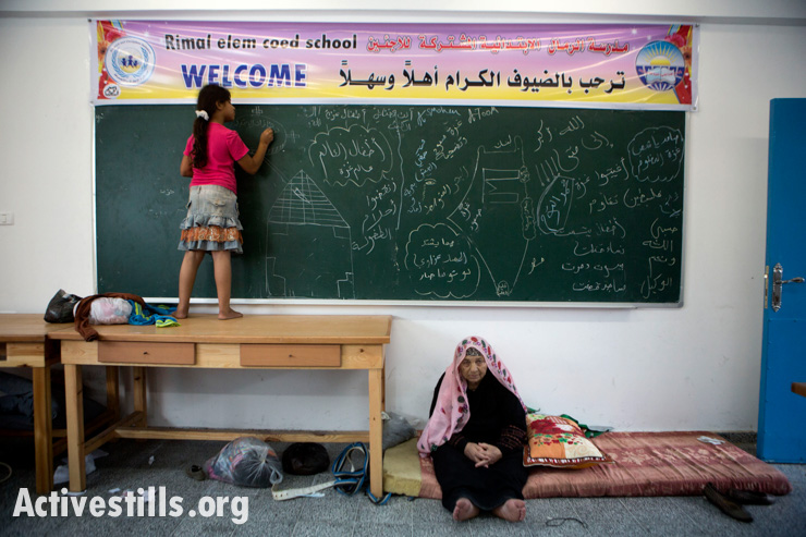 A Palestinian girl from the Al-Tom family draws on a chalk board at UNRWA's Remal Elementary School in Gaza City which is used as a temporary shelter for Palestinians fleeing the northern Gaza Strip,  July 13, 2014. People from northern Gaza left their homes after Israel dropped leaflets warning them to evacuate. Thirty members of this family are staying inside one classroom. From Salatin in north Gaza, they arrived in the morning with no belongings, hoping to return promptly to their home. The family was also displaced by Israeli attacks in 2008 and 2012.