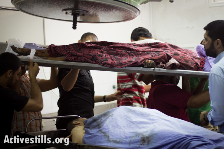 Bodies are carried from the morgue of Al Shifa Hosptial, Gaza City, July 13, 2014.