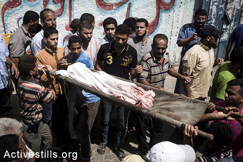 Funeral in Bani Suhaila for the 21 members of the Al-Najjar family, who were killed just before the ceasefire, east of Khan Younis, Gaza Strip, July 21, 2014.  The Al-Najjar family flew their homes in Khuza'a to take refuge fi-urther west.  Israeli attacks have killed 550 Palestinians in the current offensive, most of them civilians. Khuza'a has been under heavy attacks and many fled their village as the Israeli army physically occupies the village. Israeli attacks have killed more than 1,000 Palestinians and injured around 5,000 in the current offensive. (Anne Paq/Activestills.org)