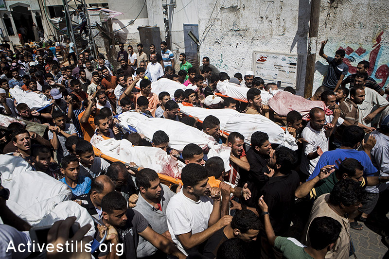 Funeral in Bani Suhaila for the 21 members of the Al-Najjar family, who were killed just before the ceasefire, east of Khan Younis, Gaza Strip, July 21, 2014.  The Al-Najjar family flew their homes in Khuza'a to take refuge fi-urther west.  Israeli attacks have killed 550 Palestinians in the current offensive, most of them civilians. Khuza'a has been under heavy attacks and many fled their village as the Israeli army physically occupies the village. Israeli attacks have killed more than 1,000 Palestinians and injured around 5,000 in the current offensive.