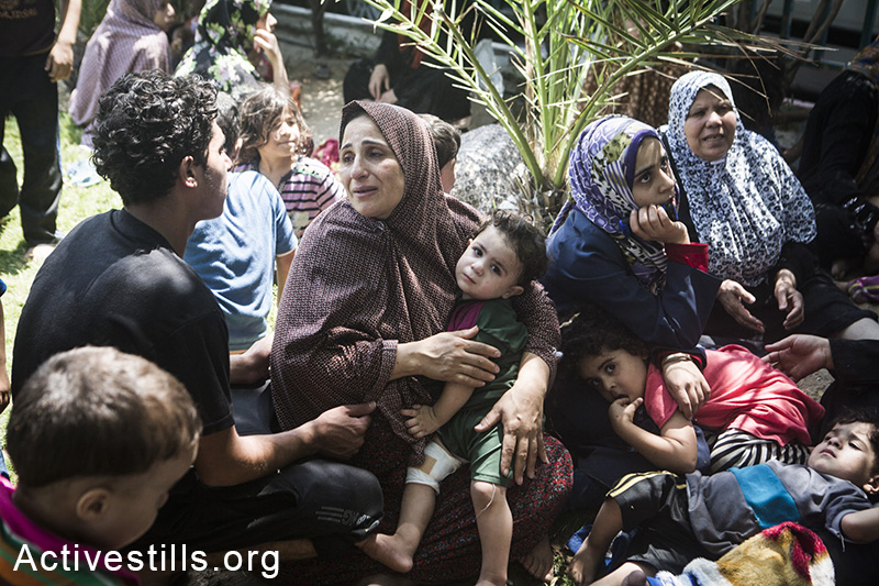 Relatives mourn on family members at the Al Shifa hospital as more bodies arrive from the Shejaiya area, July 20, 2014. (Basel Yazouri/Activestills.org)