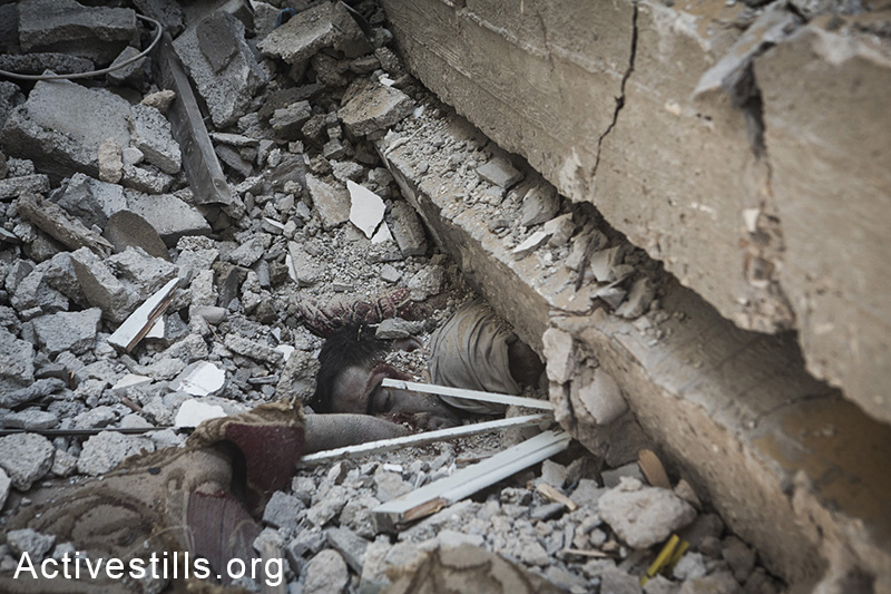 A Palestinian killed during the latest round of Israeli attacks against Al Shaja'ia is seen under the rubble of a house, Gaza City, July 20, 2014.  (Anne Paq/Activestills.org)