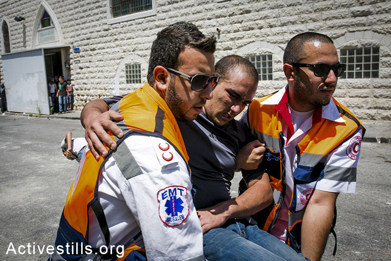 Palestinian medics evacuate a Palestinian protester during a protest following the suspected kidnapping and murder of a Palestinian teenager, East Jerusalem, July 2, 2014. Total of four journalists and a dozen protesters injured in the clashes. (Yotam Ronen/Activestills.org)