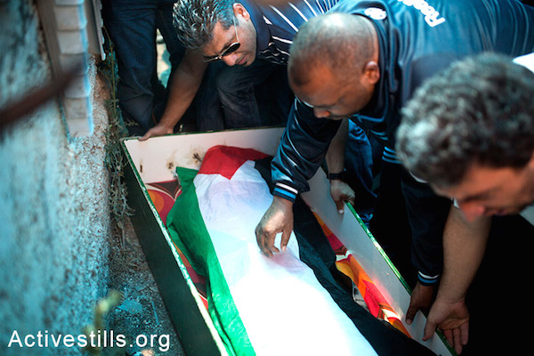 Palestinian residents of Shuafat stand above the body of Muhammad Abu Khdeir during his funeral. (photo: Activestills)