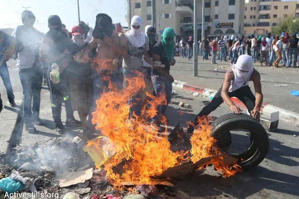 Palestinians light tires on fire during clashes with Israeli riot police during the funeral of Muhammad Abu Khdeir. (photo: Oren Ziv/Activestills.org)