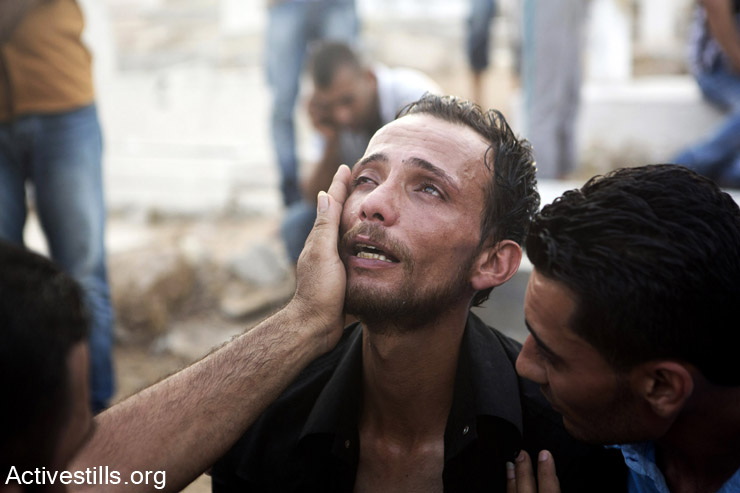 A relative of one of the children killed earlier in a playground in al-Shati refugee camp mourn at the cemetery, Gaza city, July 28, 2014. Reports indicate that 10 people, mostly children, were killed and 40 injured during the attack which took place on the first day Eid. (Anne Paq/Activestills.org)