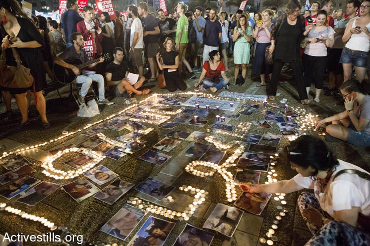Israeli activists light candles with the word "sorry" in Arabic and Hebrew, during a protest against the attack on Gaza, Rabin Square, Tel Aviv, July 26, 2014. (Keren Manor/Activestills.org)