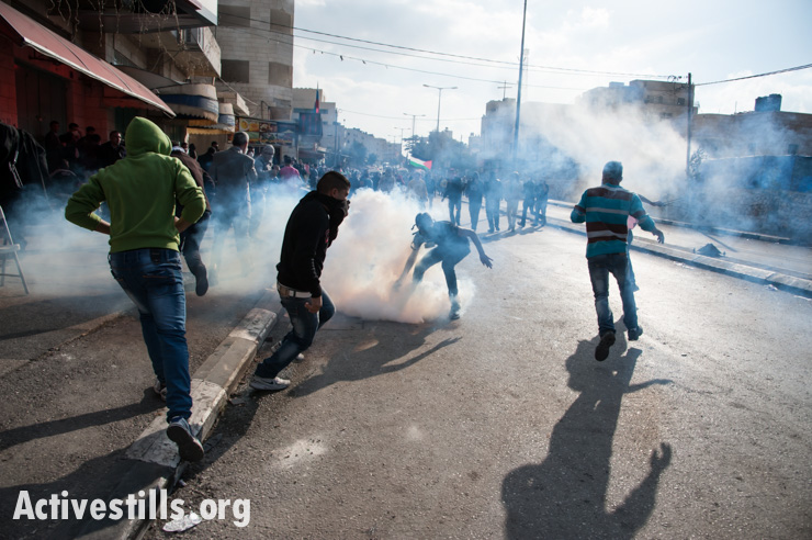 A Palestinian youth with a gas mask grabs a tear gas grenade fired by Israeli forces during clashes in the West Bank town of Bethlehem protesting Israeli attacks on Gaza, November 20, 2012.