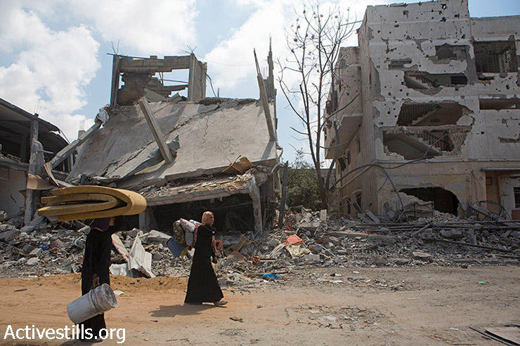 Palestinian women retrieve what belongings they can carry from their homes in Beit Hanoun, North Gaza, August 4, 2014. They had returned to their homes to quickly salvage what they could during a short ceasefire. Most Beit Hanoun residents had fled the heavily bombed areas and have been staying in UNRWA schools or with relatives. (Anne Paq/Activestills.org)
