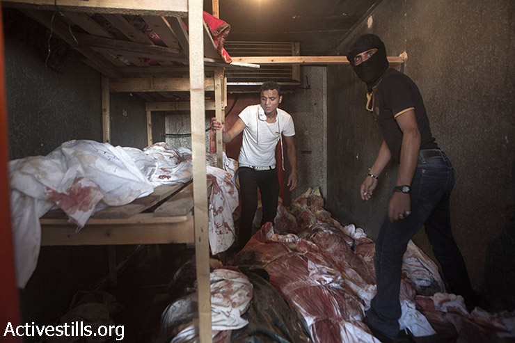 Bodies are stored in a cooler used for vegetables and flowers near Kuwaiti Hospital after it ran out of space to store corpses following Israeli attacks in Rafah, Gaza Strip, August 3, 2014. Since Al Najjar Hospital was closed, Kuwaiti, a nearby private hospital, opened its doors for emergency cases. (Anne Paq/Activestills.org)