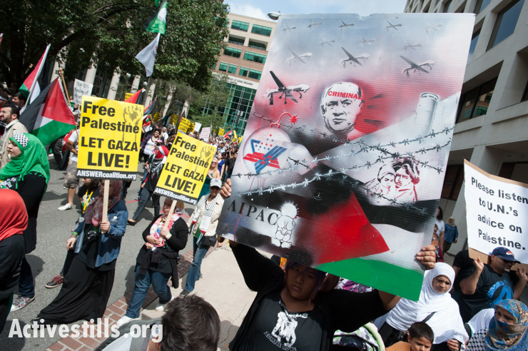 A protester carries a poster depicting Israeli Prime Minister Benjamin Netanyahu and the right-wing lobbying group AIPAC as thousands protest Israel's offensive in Gaza, Washington, D.C., August 2, 2014. So far, Israeli attacks have killed at least 1,622 Palestinians, the majority of them civilians, including 326 children.