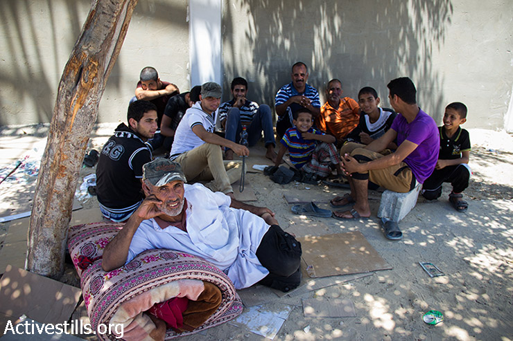 A Palestinian family from Abasan sit under a tree next to Khan Yunis hospital. The family stayed for 10 days under this tree, after they had to flee from their home due to the Israeli attack. Gaza Strip, July 24, 2014. At least 200,000 Palestinians have been displaced. (Basel Yazouri/Activestills.org)
