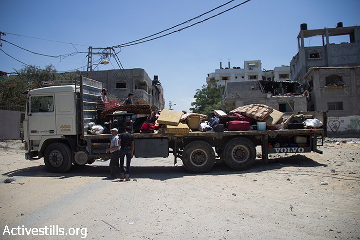 Palestinians collect their belongings in Shujaiyeh, a neighborhood in the east of Gaza City, during a ceasefire, July 27, 2014. During the ceasefire on 26 July, many Palestinians went back to Shujaiyeh to inspect the damages together with medics who attempted to rescue injured or collect bodies. Dozens of bodies were collected but many remain as Palestinians do not have all the necessary equipment to dig. Israeli attacks turned the neighborhood into a scene of utter devastation, with entire buildings flattened and thousands forced to flee. (Basel Yazouri/Activestills.org)