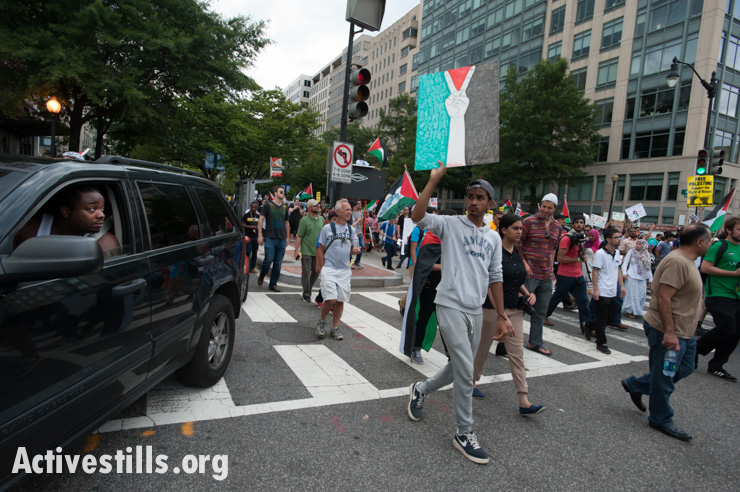 A passing motorist watches as tousands march in Washington, D.C., to protest against U.S. support for Israel's offensive in Gaza, August 2, 2014. So far, Israeli attacks have killed at least 1,622 Palestinians, the majority of them civilians, including 326 children.