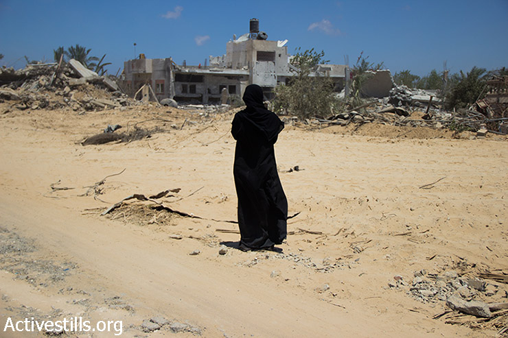 Palestinians look over Khuza'a neighborhood following bombardment by Israeli forces, Gaza Strip, August 3, 2014. Khuza'a came under heavy shelling on Monday night, July 21st. Israeli army ordered all the inhabitants of the village, nearly 10,000 people to leave. Khuza'a remined a closed military zone, and only International Committe of the Red Cross managed to secure a few brief incusions into the village to evacuate some of the injured, killed and the civilians. Most residents flew the village but some stayed behind. (Basel Yazouri/Activestills.org)