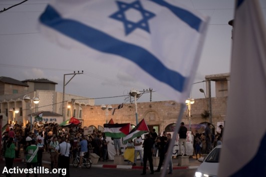 Right wing protesters demonstrates in front of Palestnians living in Israel and Israeli left wing activists as they take part in a protest against the attack on Gaza in the city of Lod, Israel, August 3, 2014 (photo: Activestills)