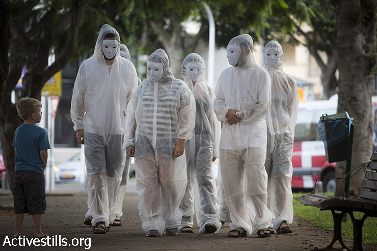 Israeli activists dressed in white and wearing white masks, walk in Rothschild boulevard in centre Tel Aviv, during a direct action in solidarity with the victims of the Gaza war, August 13, 2014. (Oren Ziv/Activestills.org)