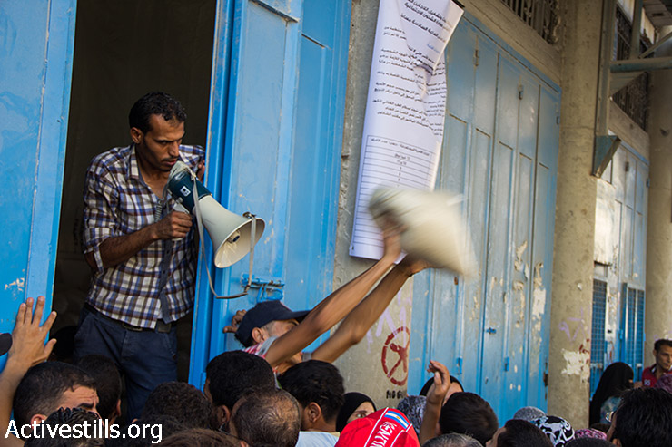 Gazans receive nutritional support from UNRWA during the cease-fire. Each family receives one bag of flour and another bag of rice. Gaza City, August 17, 2014. (Basel Yazouri/Activestills.org)