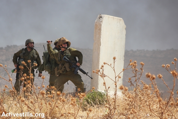 An Israeli soldier throws a stun grenade at Palestinian protesters in Beit Furik. (photo: Ahmad al-Bazz/Activestills.org)