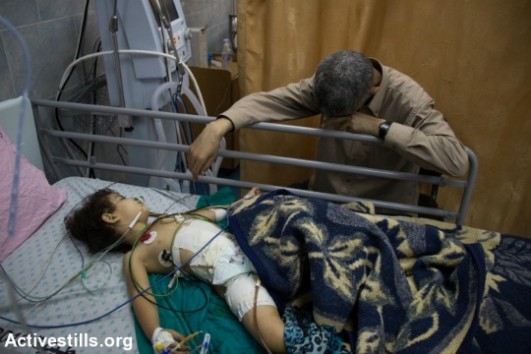 A Palestinian man watches on as a child breathes through a medical ventilator. (photo: Activestills.org)