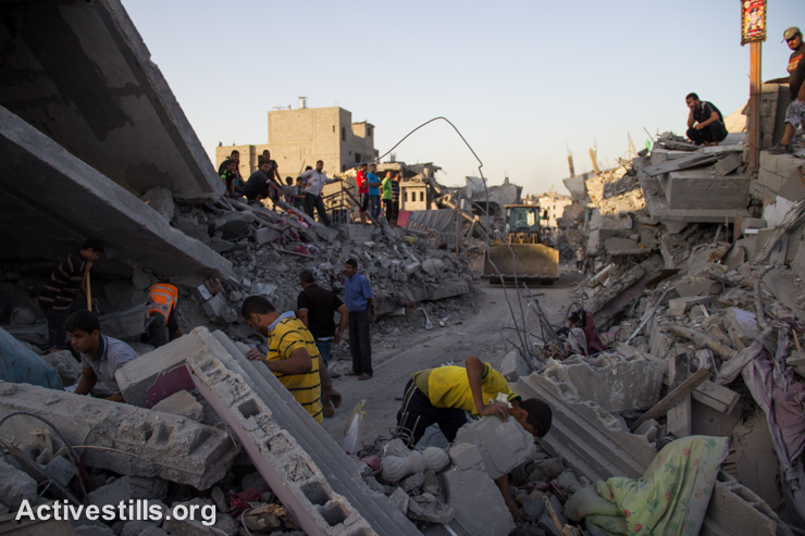 Palestinians search among the rubble in a destroyed quarter of the Shujayea neighborhood, September 4, 2014. (Activestills.org)