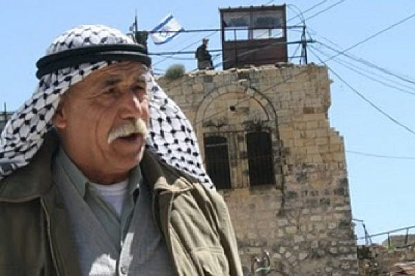 Palestinian in Hebron, with Israeli flag in the background (photo: Avidgor Charlemagne)
