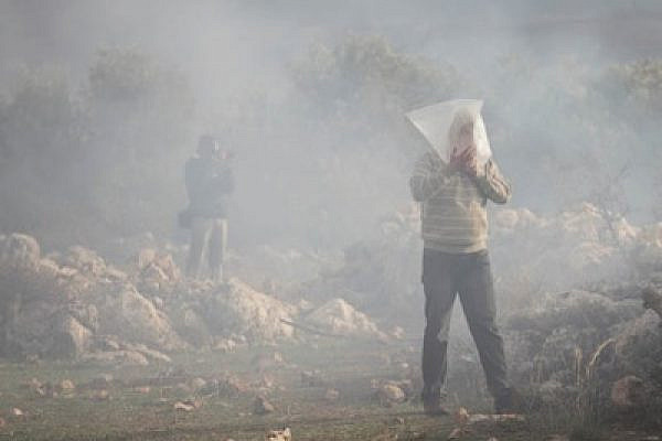 A Palestinian man in Bil'in breathes in a plastic bag while surrounded by tear gas  (photo: Oren Ziv/activestills.org)