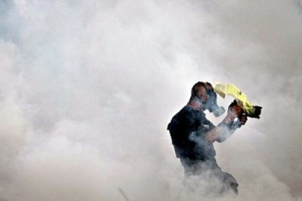 Photojournalist Mati Milstein surrounded by a cloud of tear gas. Bil'in, 31 December 2010 (photo: Fadi Arouri)