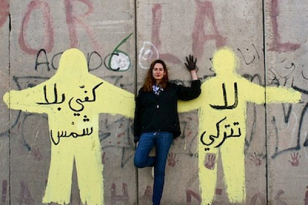 Tamara Masri, the author, against a mural she painted on the separation wall